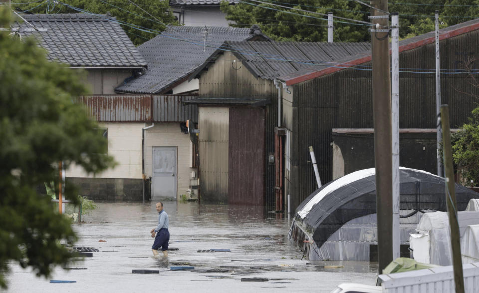 A person wades through a street due to a heavy rain in Kurume, Fukuoka prefecture, southern Japan Monday, July 10, 2023. Torrential rain is pounding southwestern Japan, triggering floods and mudslides Monday as weather officials issued emergency heavy rain warning in parts of on the southern most main island of Kyushu. (Kyodo News via AP)