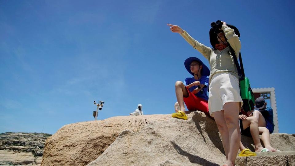 A tourist holds binoculars in front of the Taiwan Strait at the 68-nautical-mile scenic spot, one of mainland China"s closest points to the island of Taiwan, in Pingtan island, Fujian province, China August 5, 2022