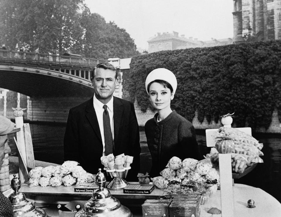 FILE - In this October 1963 file photo, actors Cary Grant and Audrey Hepburn are photographed for the film "Charade," aboard a boat in the Seine River near the Notre Dame cathedral in Paris. The Gothic structure, which sustained a devastating fire on Monday, April 15, 2019, has inspired writers, painters and filmmakers for hundreds of years. (AP Photo)