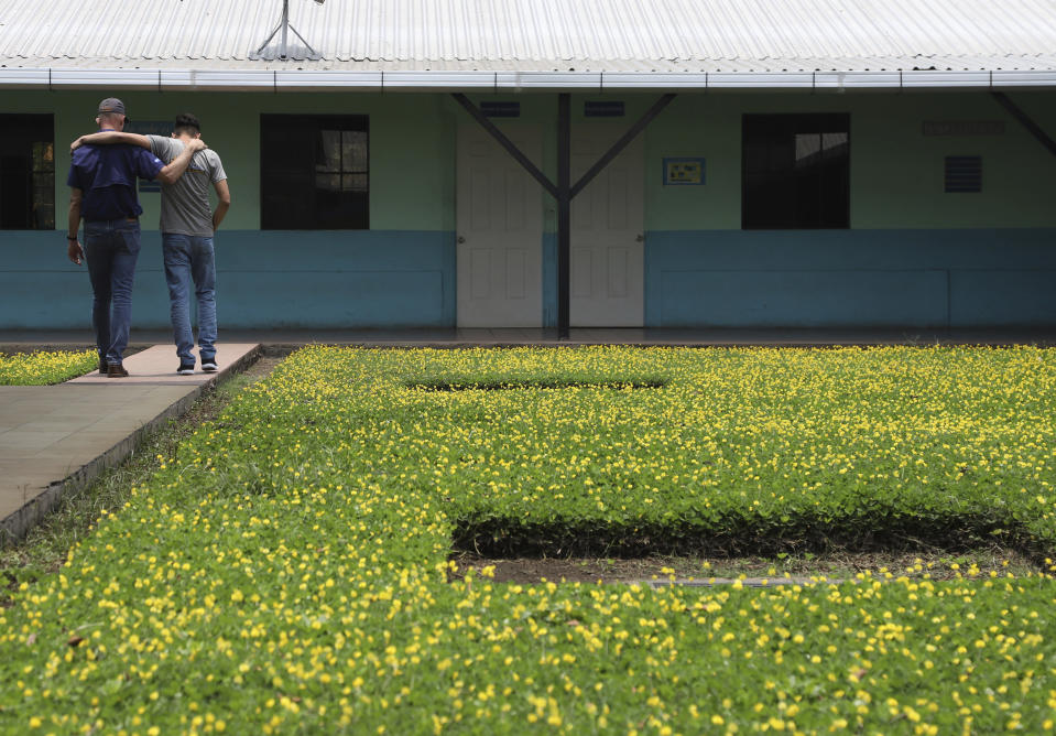 El pastor estadounidense Kenton Moody, a la izquierda, camina abrazado con un joven que estuvo en prisión por formar parte de una pandilla, en un descanso en el jardín del centro de rehabilitación de "Vida Libre", en Santa Ana, El Salvador, el sábado 29 de abril de 2023. El programa de rehabilitación para pandilleros fue fundado en El Salvador en 2021 por Moody. (AP Foto/Salvador Meléndez)