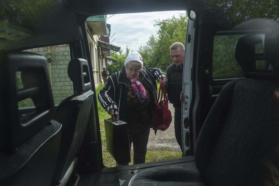 A woman gets on a volunteers car as residents are evacuated to Kharkiv, in Vovchansk, Ukraine, on Saturday, May 11, 2024. (AP Photo/Evgeniy Maloletka)