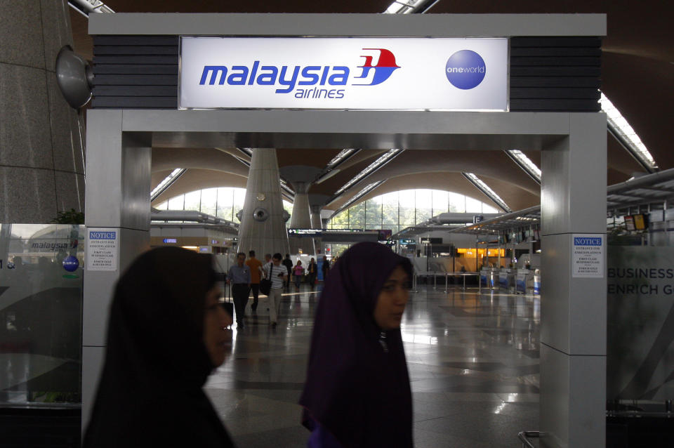 Passengers walk past a signboard of Malaysia Airlines at Kuala Lumpur International Airport in Sepang, outside Kuala Lumpur, Malaysia, Saturday, March 8, 2014. A Malaysia Airlines Boeing 777-200 carrying 239 people lost contact with air traffic control early Saturday morning on a flight from Kuala Lumpur to Beijing, and international aviation authorities still hadn't located the jetliner several hours later. (AP Photo/Lai Seng Sin)