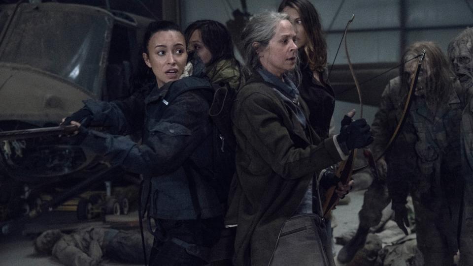 The Walking Dead Season 11 photo featuring four characters, rosita, carol, maggie, and lydia standing in circle facing outward and surrounded by zombies