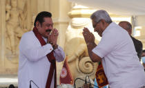 Sri Lanka’s former President Mahinda Rajapaksa, left, greets his younger brother, President Gotabaya Rajapaksa, after being sworn in as the prime minister at Kelaniya Royal Buddhist temple in Colombo, Sri Lanka, Sunday, Aug. 9, 2020. (AP Photo/Eranga Jayawardena)