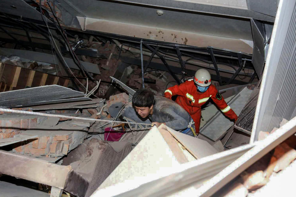 A man (L) is helped by rescuers as he is pulled from the rubble of a collapsed hotel in Quanzhou, in China's eastern Fujian province on March 7, 2020. - Around 70 people were trapped after the Xinjia Hotel collapsed on March 7 evening, officials said. (Photo by STR / AFP) / China OUT (Photo by STR/AFP via Getty Images)