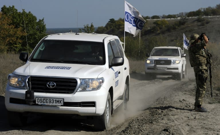 OSCE observers monitor tanks of Ukrainian forces riding from the front line near the village of Crymske in the Lugansk region on October 5, 2015