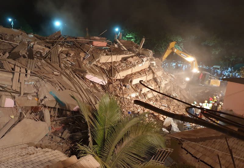 Rescue workers removes the debris as they look for survivors after a five-storey building collapsed in Mahad