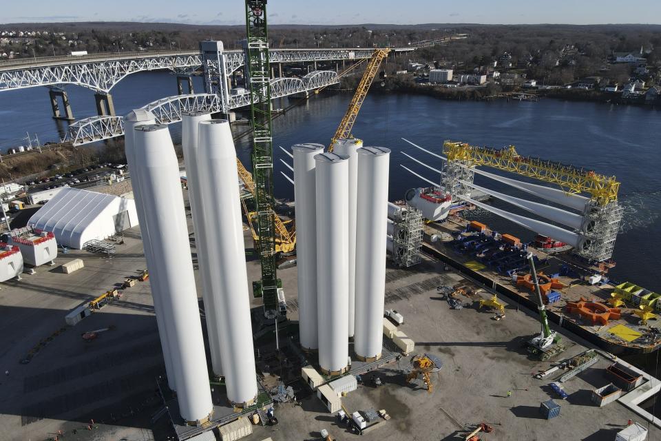 While wind farm towers, left, stand on the ground, a generator and it's blades, right, are readied for transport to the South Fork Wind farm site at State Pier in New London, Conn., Monday, Dec. 4, 2023. (AP Photo/Ted Shaffrey)