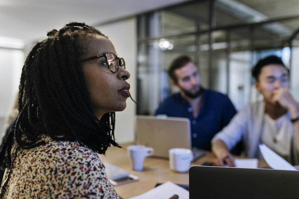 A Group of colleagues are sitting at a conference table, focusing on a presentation at a coworking space.