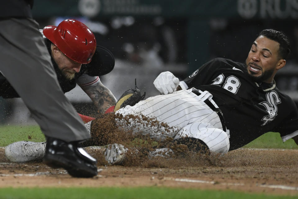 Chicago White Sox's Leury Garcia (28) slides into home plate while being tagged out by Cincinnati Reds catcher Tucker Barnhart right, while trying for an inside the park home run during the fourth inning of a baseball game Tuesday, Sept. 28, 2021, in Chicago. (AP Photo/Paul Beaty)