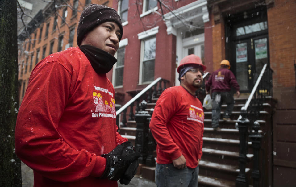 Los jornaleros mexicanos Javier Aranda (izq) y Martín García fotografiados durante un descanso afuera del edificio donde realizan trabajos de carpintería el 10 de diciembre del 2013 en Nueva York. Centros vecinales para jornaleros están ayudando a crear mejores condiciones de trabajo para esta población, negociando sueldos y beneficios. (AP Photo/Bebeto Matthews)