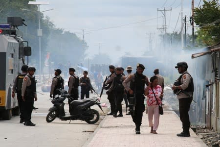 A police officer escorts a woman during a protest in Mimika, Papua