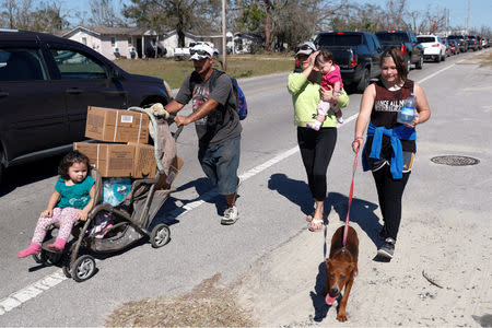 Lazaro and Amanda Perez, of Callaway, walk home with their children after picking up food and water from a public distribution location in Parker, Florida, U.S., October 13, 2018. REUTERS/Terray Sylvester