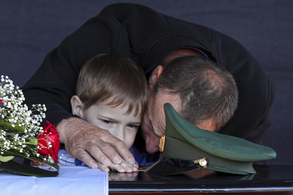 FILE - The father and son of Russian army Sgt. Daniil Dumenko, 35, who was killed in Ukraine, mourn his death at a ceremony in Volzhsky, outside Volgograd, Russia, on May 26, 2022. Nearly 50,000 Russian soldiers have died in the war in Ukraine, according to a new statistical analysis. (AP Photo, File)