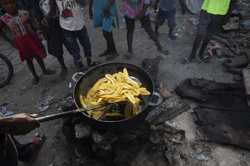 A vendor fries a batch of plantains at a market in the La Saline neighborhood near the main port entrance, partially burned by a gang two years ago, in Port-au-Prince, Haiti, Monday, Sept. 13, 2021. There could be as many as 100 gangs in Port-au-Prince; no one has an exact count and allegiances often are violently fluid. (AP Photo/Rodrigo Abd)