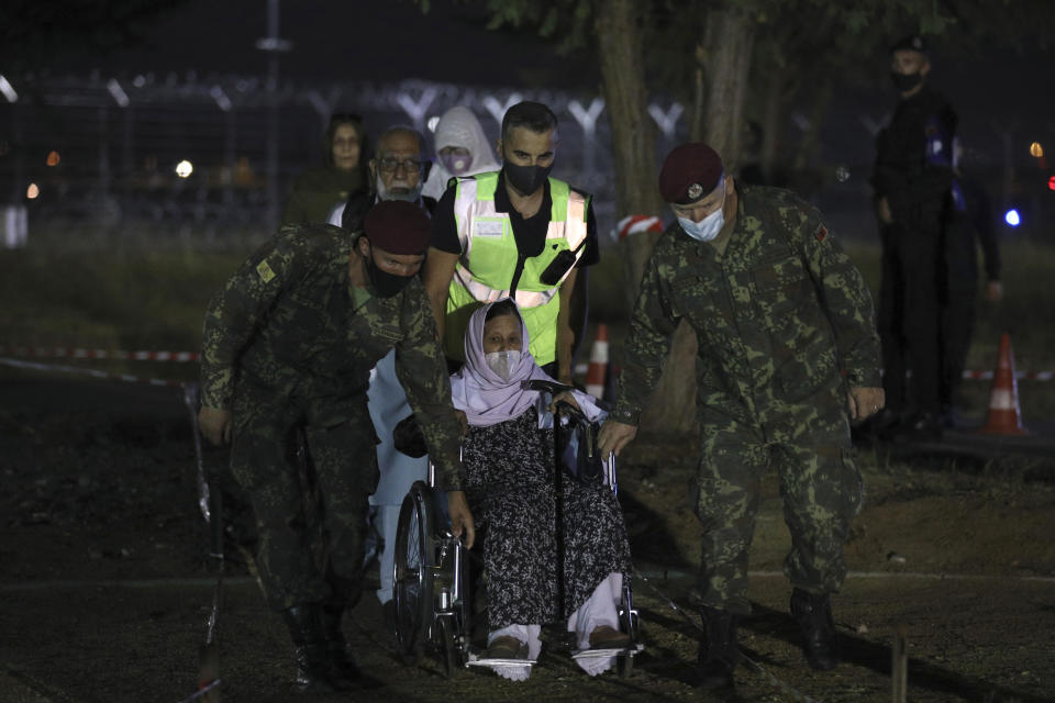 An elderly woman who evacuated from Afghanistan is helped by Albanian soldiers upon her arrival at Tirana International Airport in Tirana, Albania, Friday, Aug 27, 2021. A government decision has planned that the Afghans may stay at least a year during which they will proceed with their application for special visas before they move on to the U.S. for final settlement. (AP Photo/Franc Zhurda)