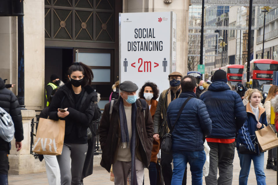 LONDON, UNITED KINGDOM - 2020/12/02: People walk past a Social Distancing sign on Oxford Street. Thousands of people poured into West End stores as England eased its month-long lockdown. (Photo by Vuk Valcic/SOPA Images/LightRocket via Getty Images)