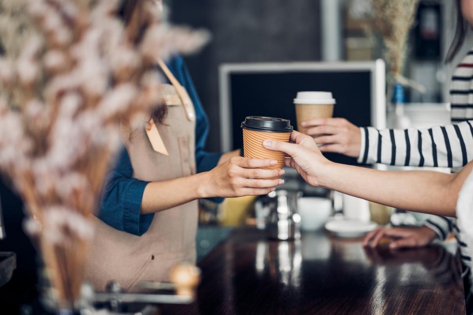 Barista handing coffee to customer.