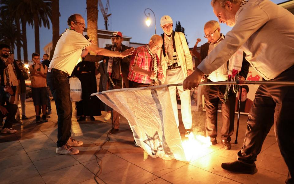 Demonstrators burn an Israeli flag in front of the parliament building in Rabat