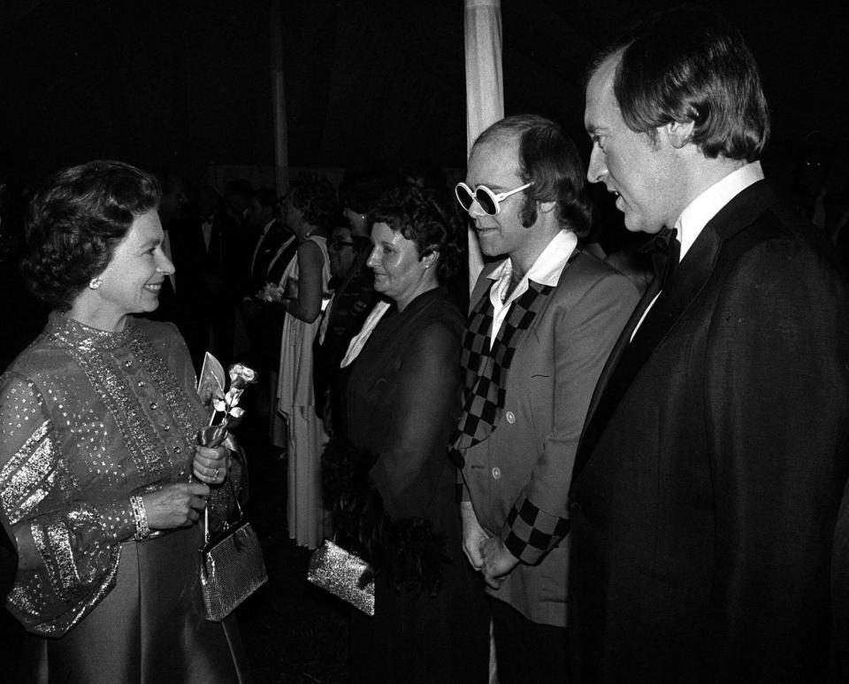 Bespectacled pop star Elton John and television personality David Frost being presented to the Queen at Windsor when they were among a host of stars appearing in a gala variety performance in the Big Top at Home Park in aid of the Queen's Silver Jubilee Appeal. (Photo by PA Images via Getty Images)
