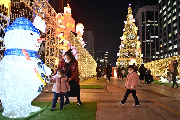 Las personas posan para las fotos mientras visitan una exhibición de luces navideñas en el centro de Seúl, el 23 de diciembre de 2021
