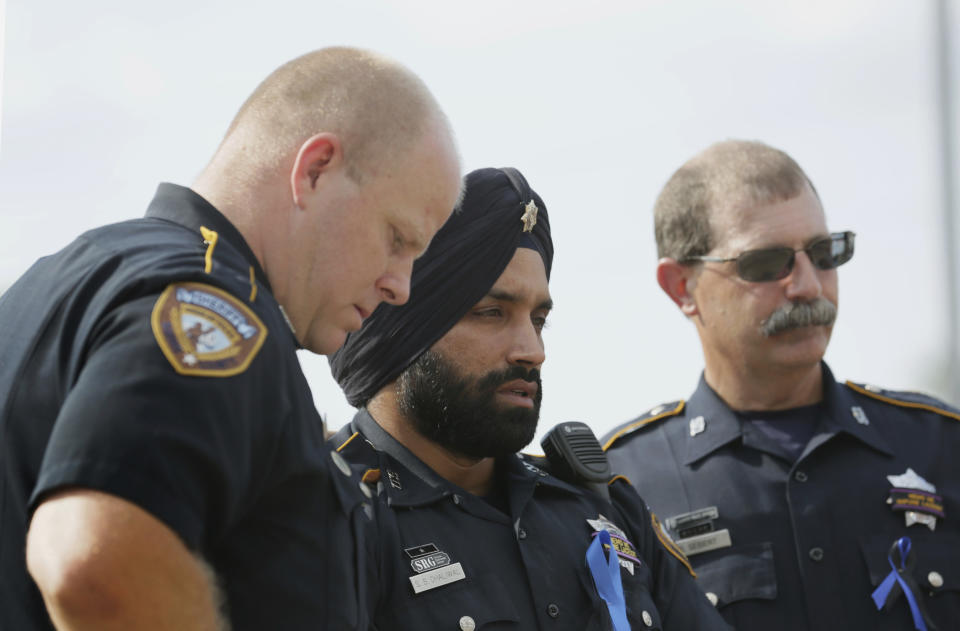 In this Aug. 30, 2015, photo, Harris County Sheriff's Deputy Sandeep Dhaliwal, center, grieves with Deputies Dixon, left, and Seibert, right, at a memorial for Deputy Darren Goforth, at the Chevron where he was killed, in Houston. Dhaliwal was shot and killed while making a traffic stop Friday, Sept. 27, 2019, near Houston. (Jon Shapley/Houston Chronicle via AP)