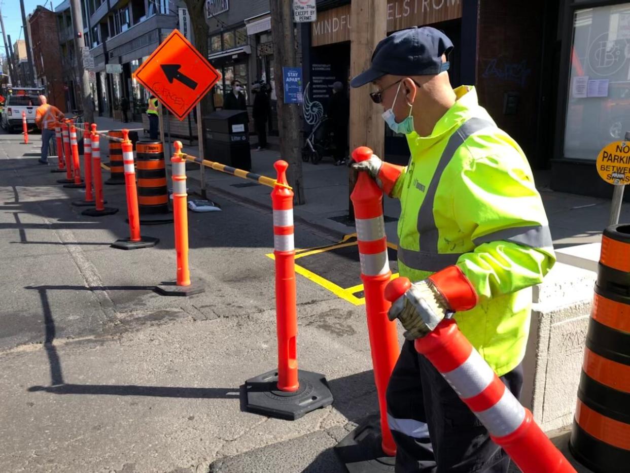 A city worker puts equipment in place for the CaféTO program. This year, the city says a majority of patios will be ready for the Victoria Day weekend. (Robert Krbavac/CBC - image credit)