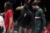 New Orleans Pelicans' Steven Adams, left, Zion Williamson, center and Lonzo Ball greet teammates walking off the court for halftime of an NBA basketball game against the Dallas Mavericks in Dallas, Wednesday, May 12, 2021. The three did not play in the game. (AP Photo/Tony Gutierrez)