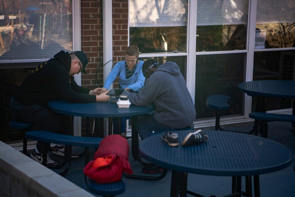 Christie and Jeffery Glenn bow their heads in prayer with Dustin Mailman, a pastor at Trinity United Methodist Church, after lunch at Haywood Street Congregation, November 8, 2023.