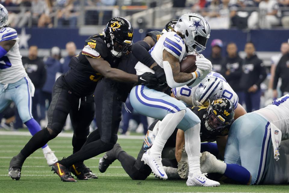 Dallas Cowboys running back Ezekiel Elliott (21) is stopped trying to advance the ball by Washington Commanders linebacker Jamin Davis (52) and others in the first half of a NFL football game in Arlington, Texas, Sunday, Oct. 2, 2022. (AP Photo/Michael Ainsworth)