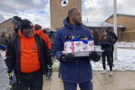Michigan linebacker Nikhai Hill-Green holds a tray containing a turkey, vegetables and other items during a giveaway event outside a school in Ypsilanti, Mich., on Sunday, Nov. 20, 2022. Hill-Green took part in the charitable effort, which was spearheaded by his friend and Michigan teammate Blake Corum, less than a week before their third-ranked Wolverines play No. 2 Ohio State. (AP Photo/Mike Householder)