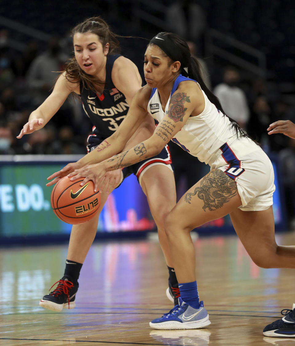 Connecticut guard Caroline Ducharme (33) and DePaul guard Sonya Morris reach for a loose ball in the first half of an NCAA college basketball game at Wintrust Arena in Chicago on Wednesday, Jan. 26, 2022. (Chris Sweda/Chicago Tribune via AP)