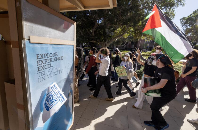 Los Angeles, CA - November 08: UCLA students march past an ad for a program at an Israeli university as they rally for Palestine on the UCLA campus in Westwood Wednesday, Nov. 8, 2023 in Los Angeles, CA. (Brian van der Brug / Los Angeles Times)