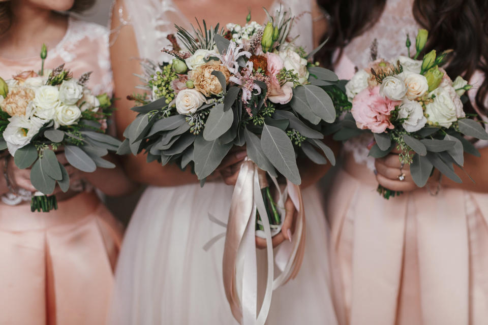 Three bridesmaids stand next to each other holding bouquets