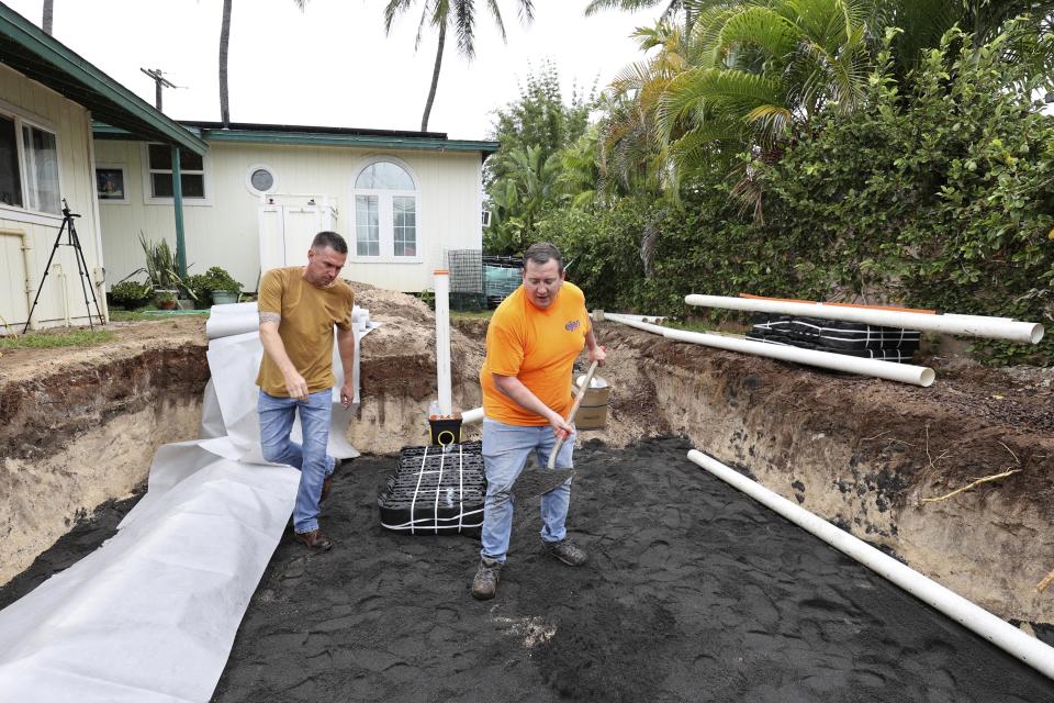 Jim King, right, CEO of Eljen Corporation, and Lance Bates, a distributor of Ejen Corporation products, demonstrate how to install a septic tank and leach field system to replace a residential cesspool, May 11, 2023, in Waialua, Hawaii. Hawaii has 83,000 of cesspools, more than any other U.S. state, and many of them are close to the shoreline. (AP Photo/Marco Garcia)