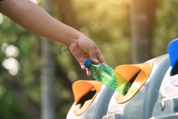 Person recycling a plastic bottle - Getty Images