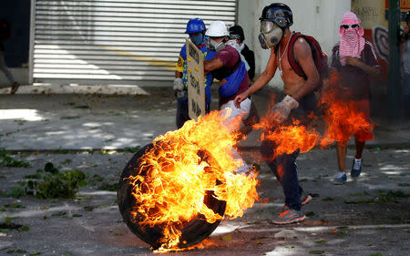 Demonstrators use a tire on fire to block a street at a rally during a strike called to protest against Venezuelan President Nicolas Maduro's government in Caracas, Venezuela July 26, 2017. REUTERS/Andres Martinez Casares
