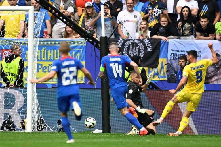 El delantero ucraniano Roman Yaremchuk (de amarillo a la derecha) supera la salida del portero eslovaco Martin Dubravka para marcar el gol de la victoria por 2-1 en partido del grupo E de la Eurocopa, en Düsseldorf el 21 de junio de 2024 (INA FASSBENDER)