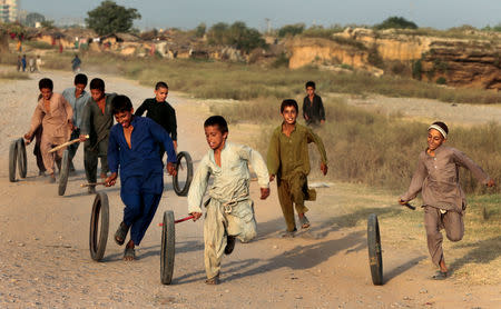 FILE PHOTO: Afghan refugee children play with tyres in Islamabad, Pakistan, October 6, 2017. REUTERS/Caren Firouz/File Photo