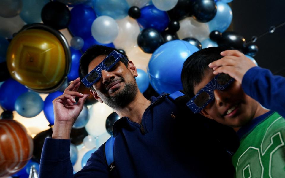 Passengers wear solar eclipse glasses as they get ready to board a plane en route to Detroit, Michigan