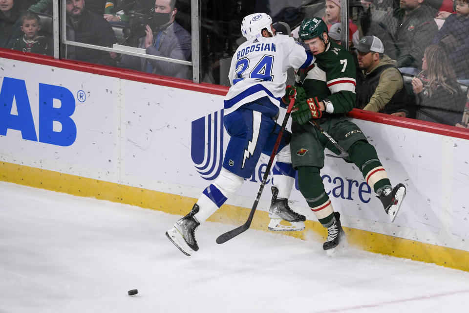 Tampa Bay Lightning defenseman Zach Bogosian, left, checks Minnesota Wild Nico Sturm into the glass during the third period of an NHL hockey game Sunday, Nov. 28, 2021, in St. Paul, Minn. (AP Photo/Craig Lassig)