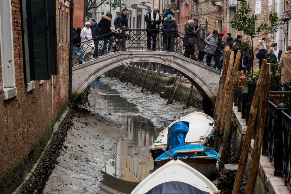 Boats are docked along a dried canal during a low tide in Venice, Italy, Tuesday, Feb. 21, 2023. Some of&nbsp;Venice's secondary canals have practically dried up lately due a prolonged spell of low tides linked to a lingering high-pressure weather system.