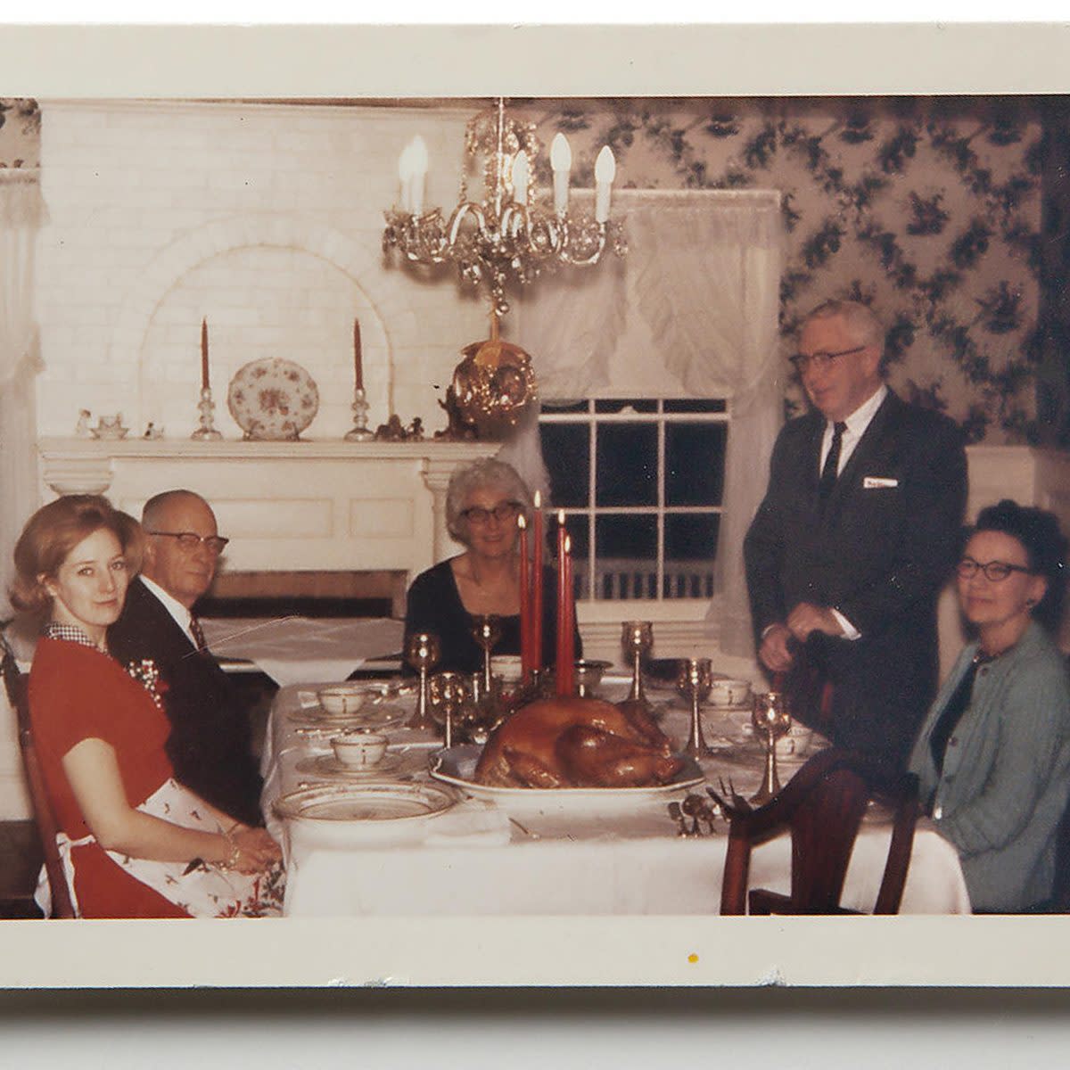 people around thanksgiving table with lit red candles