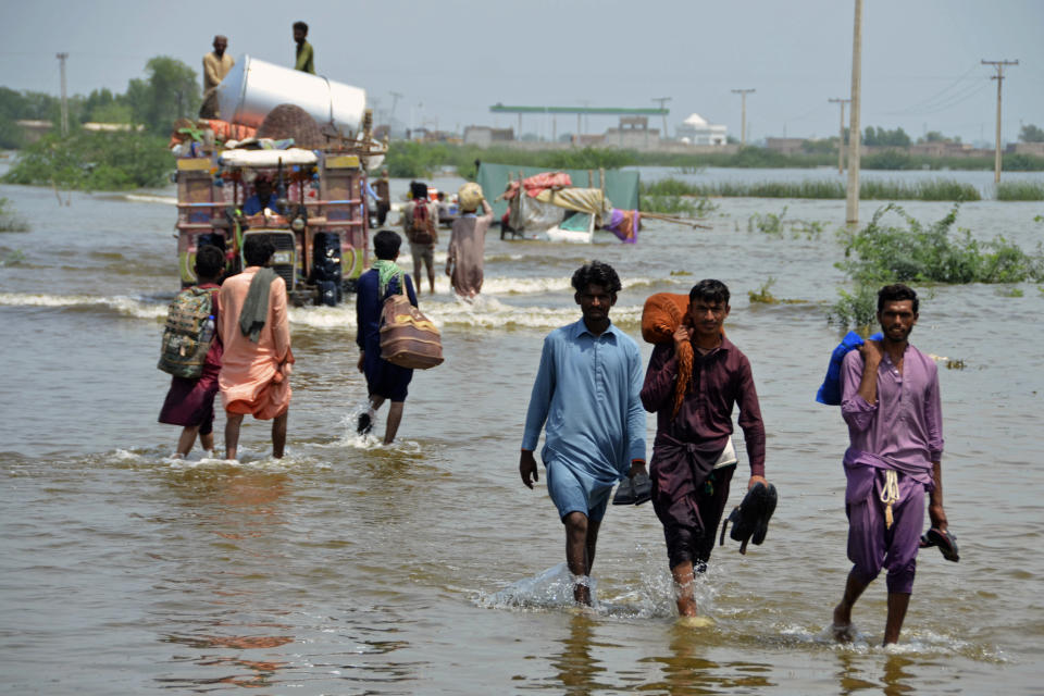 People wade through a flooded area of Sohbatpur, a district of Pakistan's southwestern Baluchistan province, Monday, Aug. 29, 2022. International aid was reaching Pakistan on Monday, as the military and volunteers desperately tried to evacuate many thousands stranded by widespread flooding driven by "monster monsoons" that have claimed more than 1,000 lives this summer. (AP Photo/Zahid Hussain)