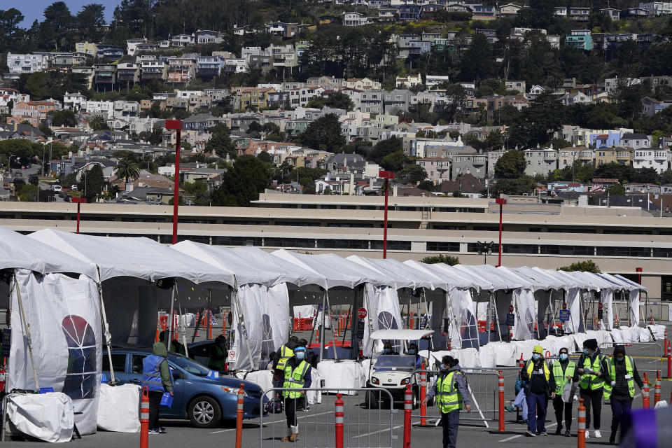 Healthcare workers tend to people in cars at a drive up vaccination center at City College of San Francisco during the coronavirus pandemic in San Francisco, Thursday, March 25, 2021. (AP Photo/Jeff Chiu)