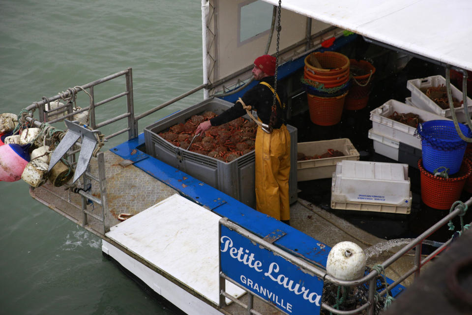 A fisherman unloads crabs from a French trawler coming from the British waters, in the port of Granville, Normandy, Monday, Nov. 1, 2021. France has threatened to bar British boats from some of its ports and tighten checks on boats and trucks carrying British goods if more French vessels aren't licensed to fish in U.K. waters by Tuesday Oct.2, 2021. French fishing crews stood their ground, demanding a political solution to a local dispute that has become the latest battleground between Britain and the European Union. (AP Photo/Nicolas Garriga)