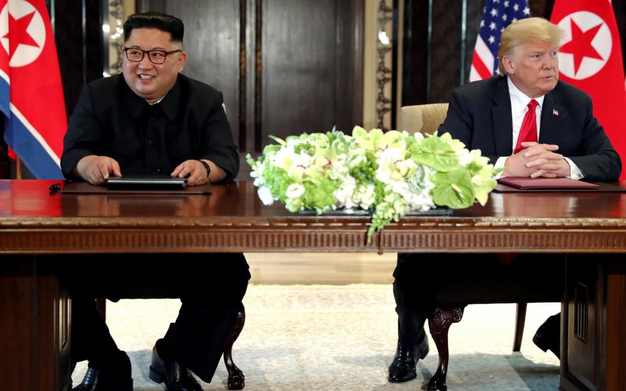 US President Donald Trump and North Korea's leader Kim Jong Un hold a signing ceremony at the conclusion of their summit on June 12, 2018 - REUTERS