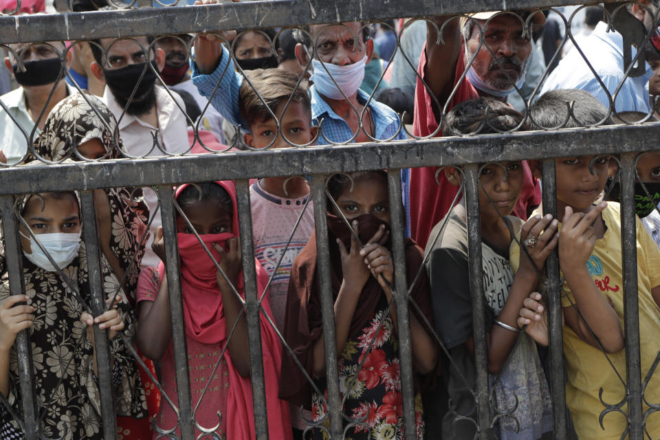 Children wait to receive food distributed in a slum during a lockdown due to the coronavirus pandemic in Mumbai, India, Saturday, April 18, 2020. The organization says they serve thousands of people daily at different regions in the city since the lockdown started in the country. (AP Photo/Rajanish Kakade)