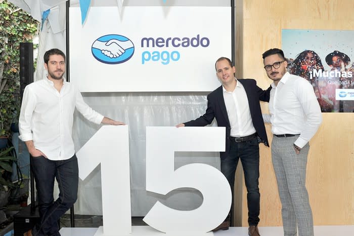 Three people in front of a MercadoPago sign and the number 15.