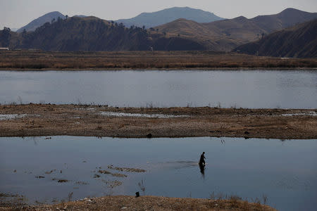 A man carrying fishing net wades through shallow waters of the Yalu River between China and North Korea, north of Dandong, China's Liaoning province, April 1, 2017. REUTERS/Damir Sagolj